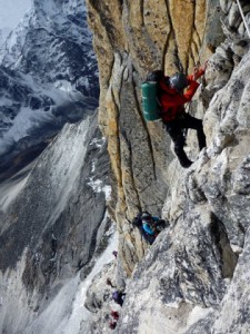 Climber descending below grey tower on Ama